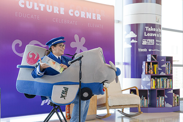 Phoenix Sky Harbor mascot, Amelia, reading a book to a group of children at the March 2026 Culture Corner event
