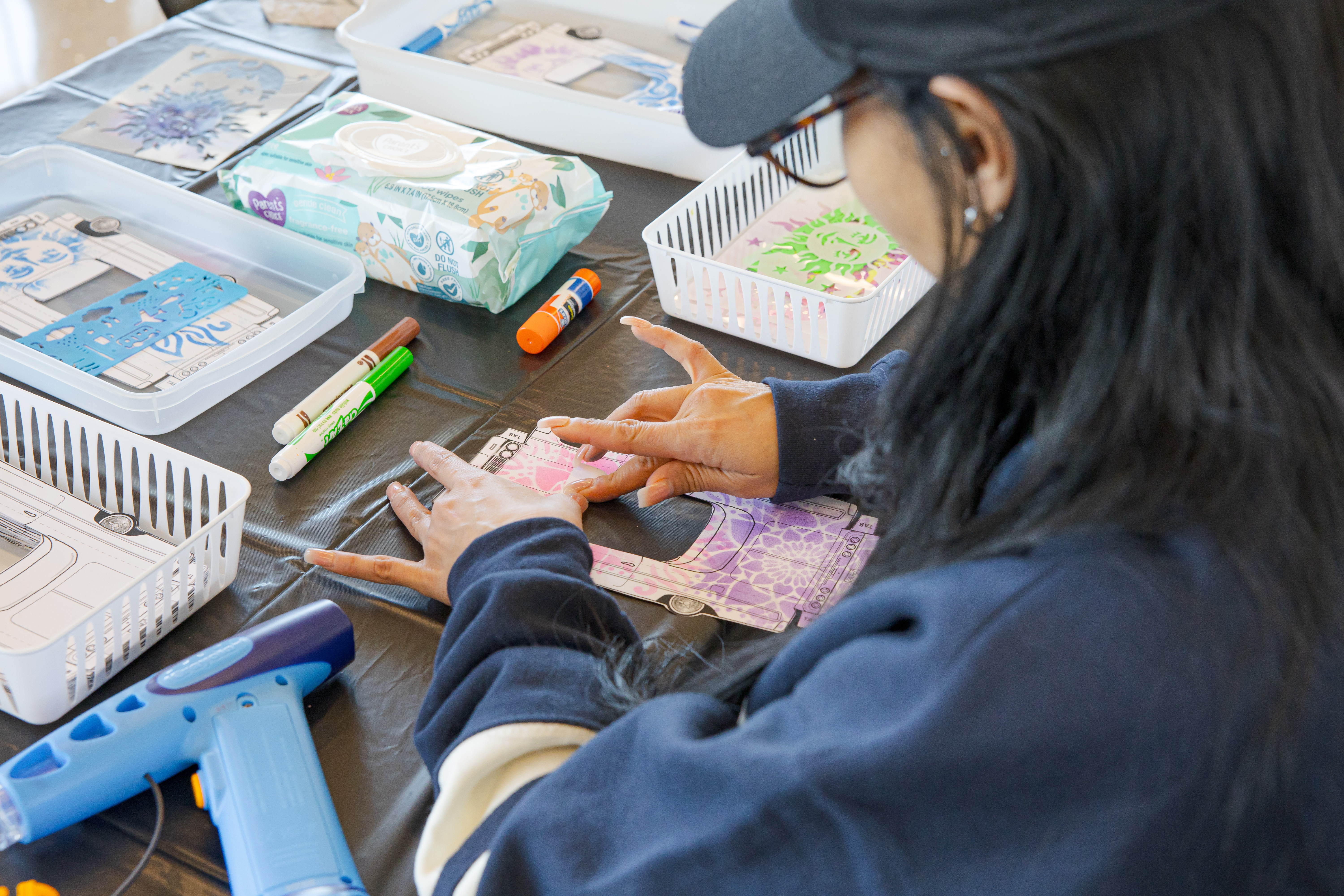 Picture of a woman with a hat and glasses working on a craft