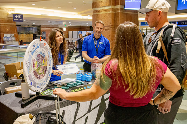 Travelers standing in front of a table and spinning a prize wheel for Earth Day