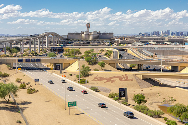 A daytime view of Phoenix Sky Harbor Airport with a deep blue sky and the city of Phoenix skyline in the background