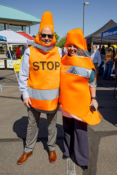 Two airport employees wearing traffic cone costumes pose for a photo at the safety fair event
