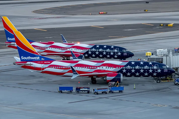 Two Southwest Airlines planes sitting next to each other at the airport painted with American flag livery