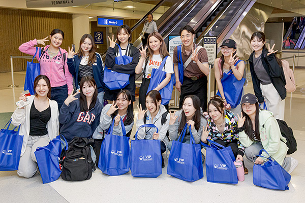 A group photo of ASU Japanese students in Terminal 4 all smiling and making the ASU hand sign