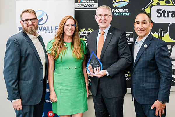 Phoenix Aviation Director Chad Makovsky posing with three other people while holding the West Valley Regional Chamber’s Regional Impact Award